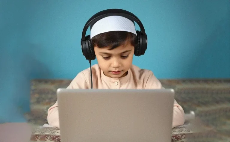 8-year-old kid wearing a white prayer cap and headphones, engaged in an online Quran class on his laptop, focused on learning.